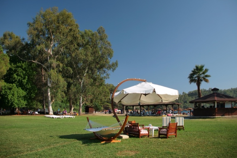 Hammock and parasol on a shady lawn at Günlüklü Bay near Fethiye, Türkiye
